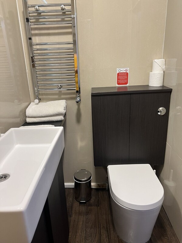 A bathroom with a white sink, a toilet, and a dark wooden cabinet.