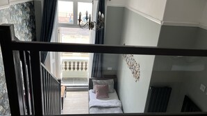 A bedroom with a bed, a chandelier, and a view of the outside balcony. - Astral Lodge (Hastings)