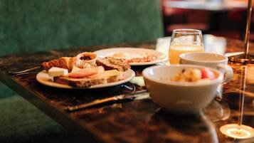Una mesa de desayuno con platos de comida, un bol y un vaso de jugo.