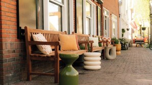Espace extérieur aménagé avec des bancs et des jardinières le long d’un bâtiment en briques.