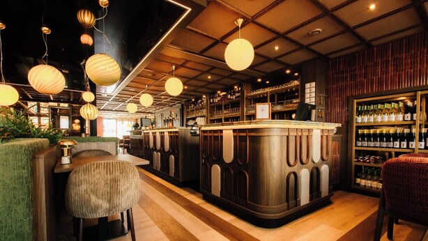 Un espace bar avec des meubles en bois, des lampes sphériques suspendues et un présentoir à vin.