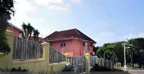 A residential building with a red roof, a gated entrance, and a clear sky.