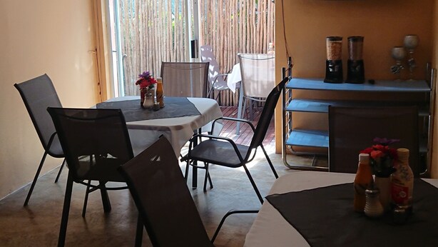 A dining area with a table, chairs, and a television mounted on the wall. - KZN Park View Guest House (Durban)