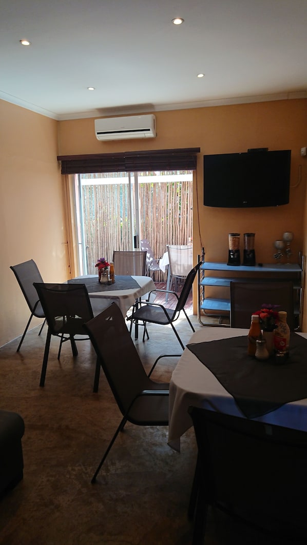 A dining area with a table, chairs, and a television mounted on the wall. - KZN Park View Guest House (Durban)