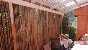 Un patio al aire libre con piso de madera, mesas con manteles blancos y sillas.