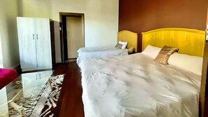 Habitación de hotel con una cama grande, un armario y una puerta que da a otra habitación.