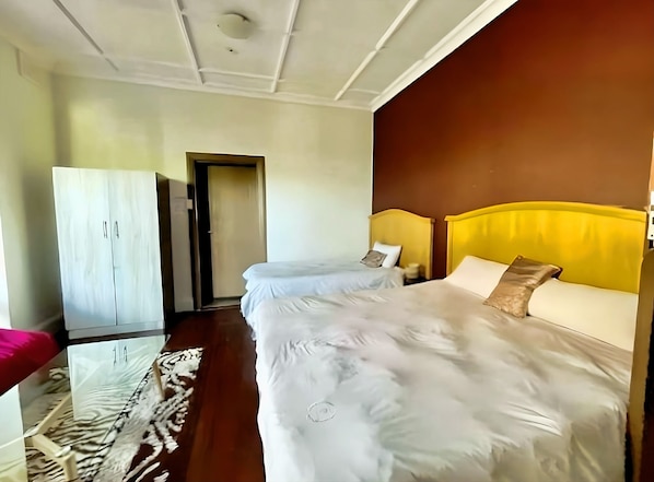 Habitación de hotel con una cama grande, un armario y una puerta que da a otra habitación.