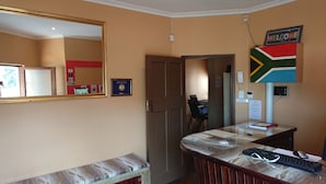 Una habitación de hotel con un espejo grande, un escritorio con una computadora, una silla y un banco.