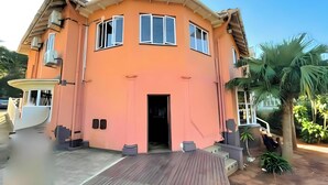 Una casa de dos pisos con techo curvo, un balcón y una terraza de madera.