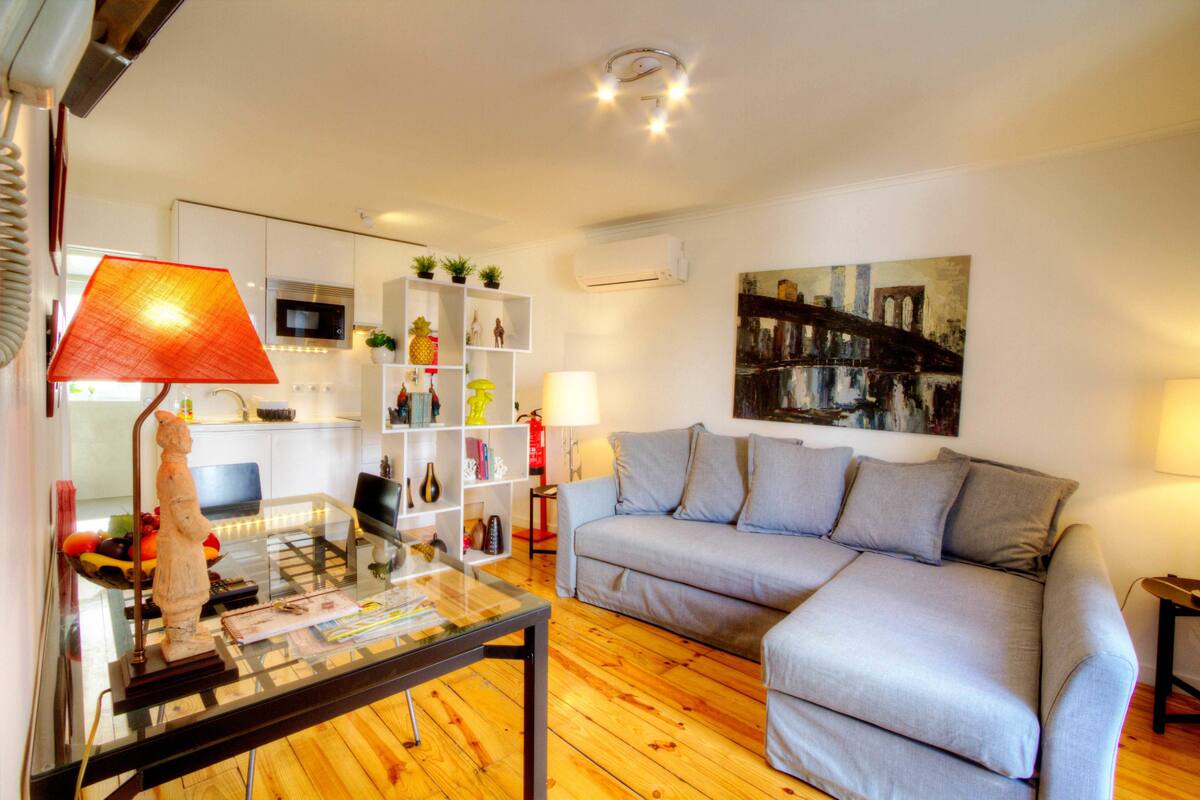 Un salon moderne avec un canapé, une table basse en verre et une bibliothèque.