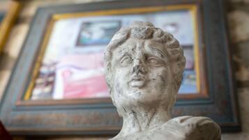 Una escultura en busto de mármol frente a una obra de arte enmarco.