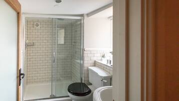 Une salle de bain avec une douche à parois de verre, des toilettes et une baignoire.