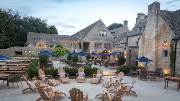 A stone building with outdoor seating and umbrellas. - The Frogmill (Cheltenham)