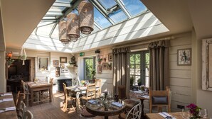 A restaurant with a high ceiling, wooden tables, and chairs, and a skylight. - The Frogmill (Cheltenham)