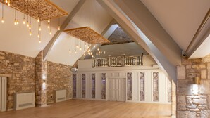 A spacious room with exposed stone walls, wooden beams, and hanging light fixtures. - The Frogmill (Cheltenham)