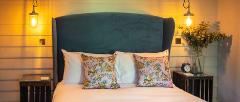A neatly made bed with floral pillows, a dark headboard, and two bedside tables with lamps.