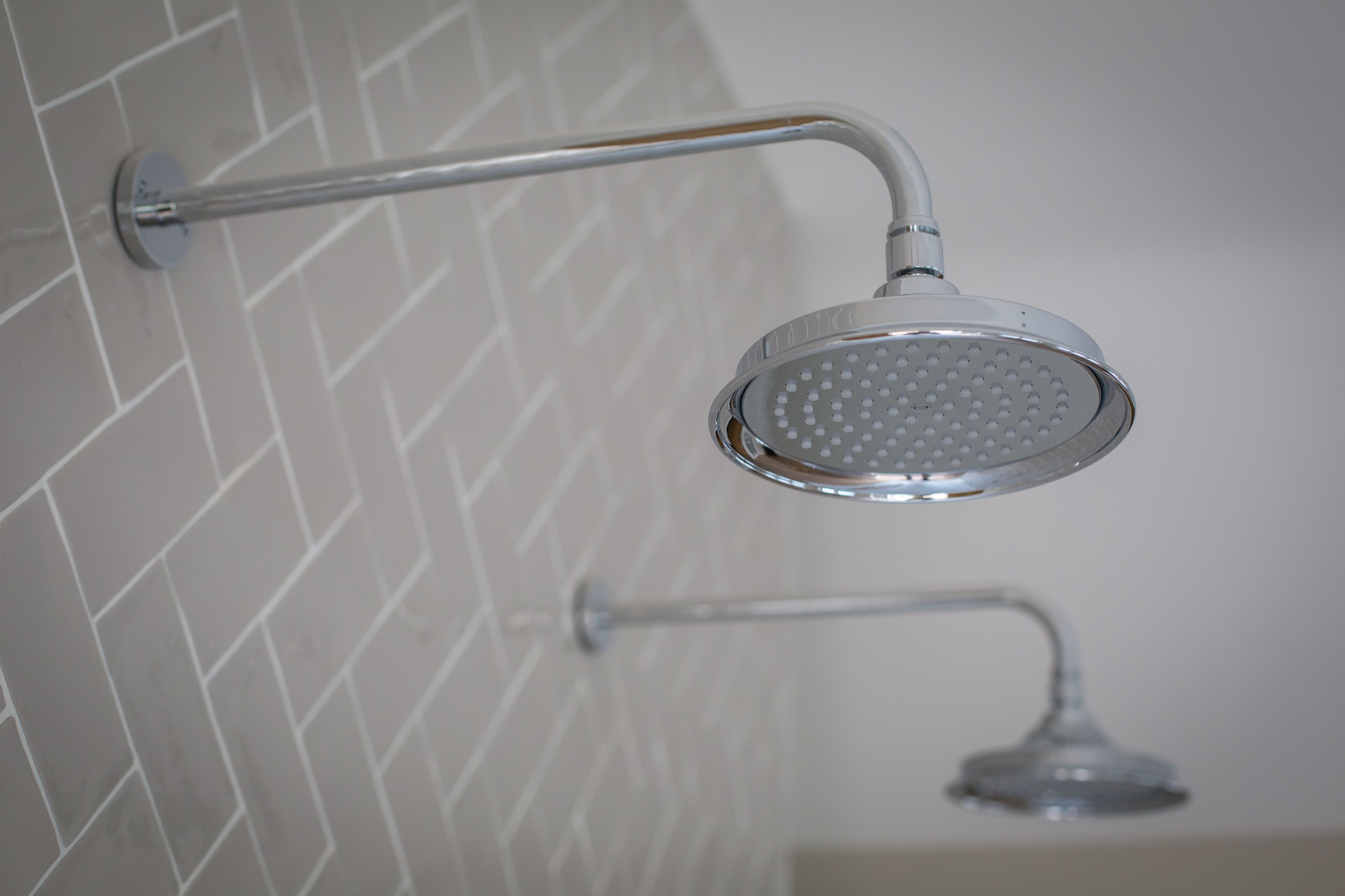 A shower with a handheld attachment and a wall-mounted showerhead.