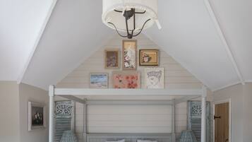 A bedroom with a sloped ceiling, a bed with a headboard, and wall-mounted artwork.