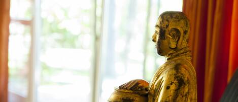 A statue in a room with a large window and curtains.