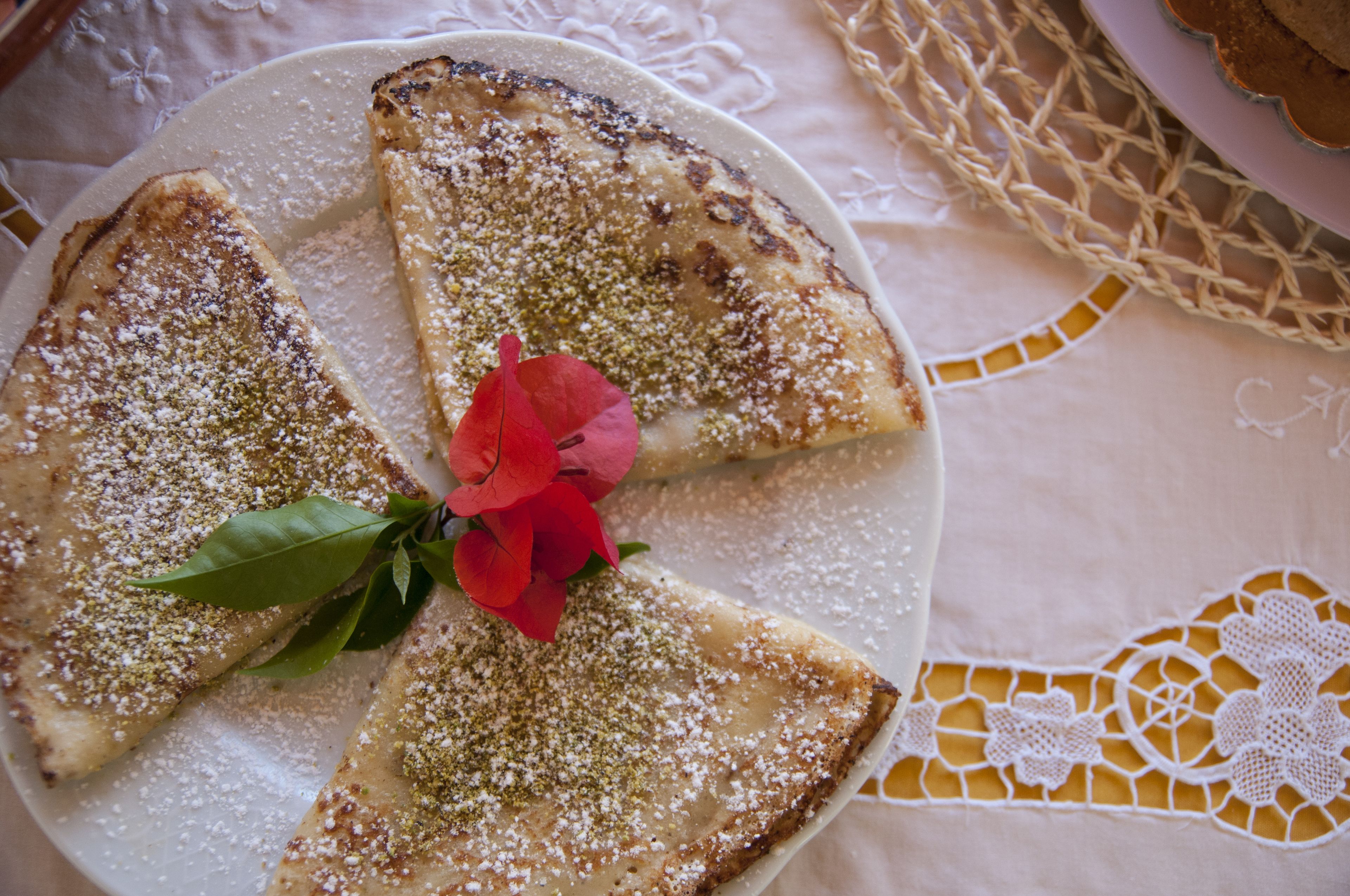 A plate with slices of bread topped with powdered sugar and a red flower.