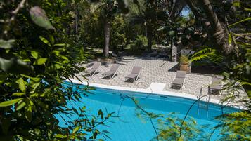 Una piscina al aire libre de temporada, sillones reclinables de piscina