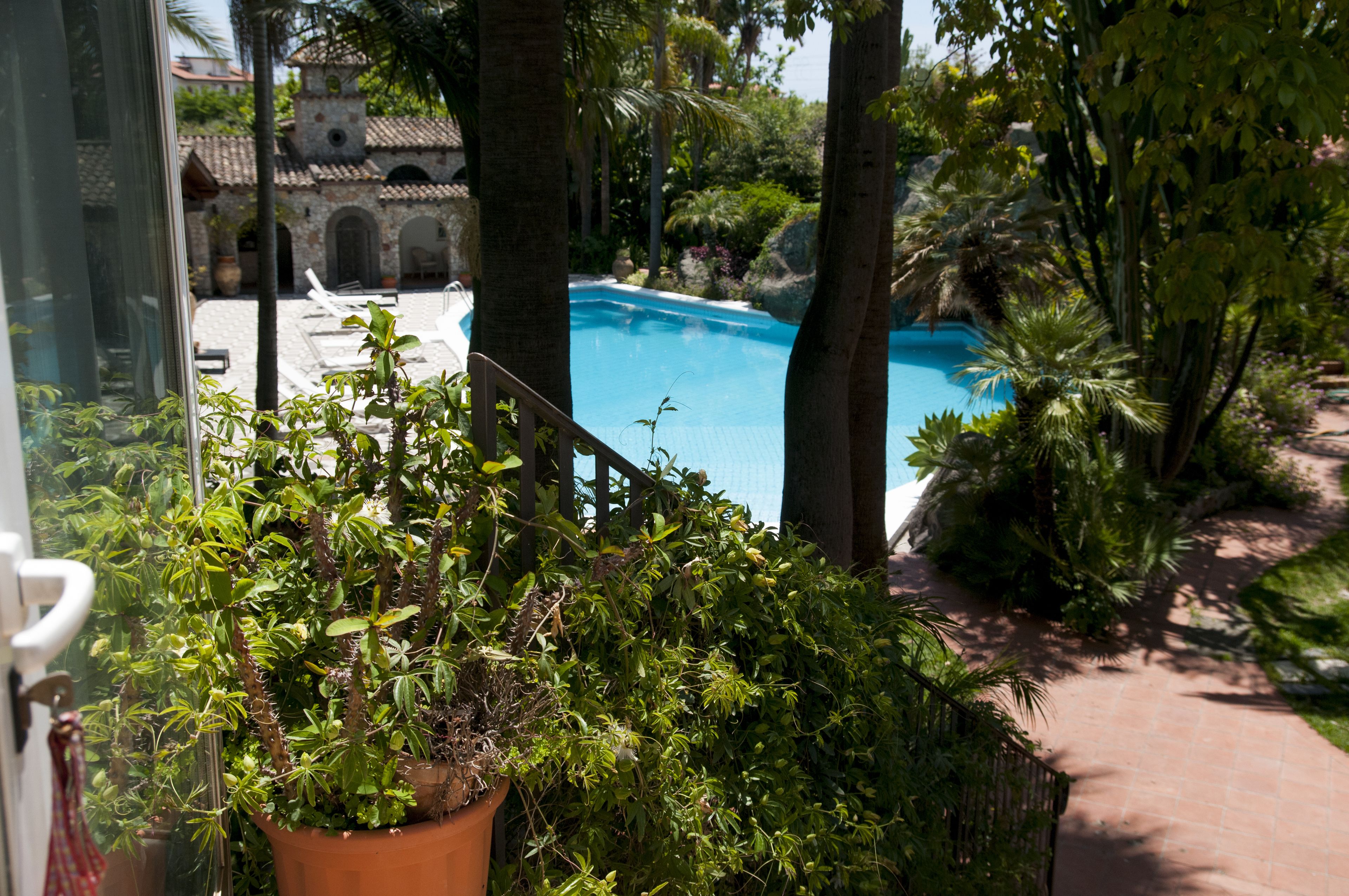 A pool surrounded by lush greenery and a traditional building in the background.