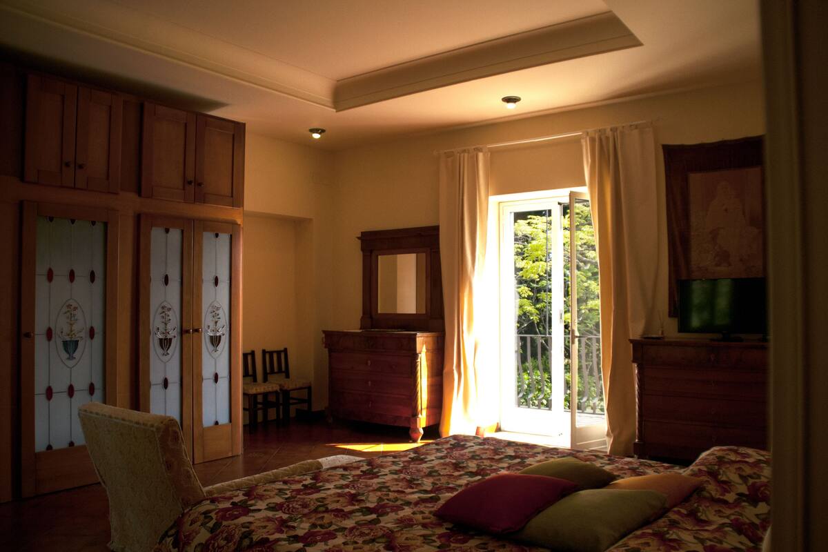 Un dormitorio con cama, cómoda, silla y ventana con cortinas.