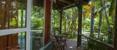 Un espace extérieur abrité, doté d’une table et de chaises, et entouré d’une végétation tropicale luxuriante.