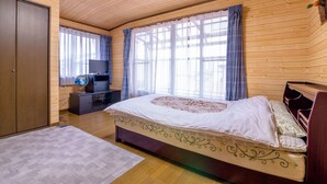 A bedroom with a wooden ceiling, a bed with a floral bedspread, a dresser, a television on a stand, and a globe on the dresser. - Asahi (Fujiyoshida)