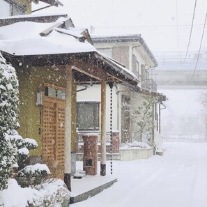 Une rue résidentielle bordée de maisons enneigées, caractérisée par une architecture traditionnelle avec des éléments en bois et un porche abrité.
