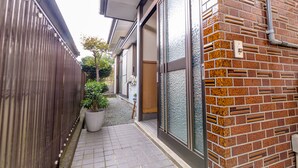 A narrow pathway leading to a building with a brick facade and large glass doors. - Asahi (Fujiyoshida)