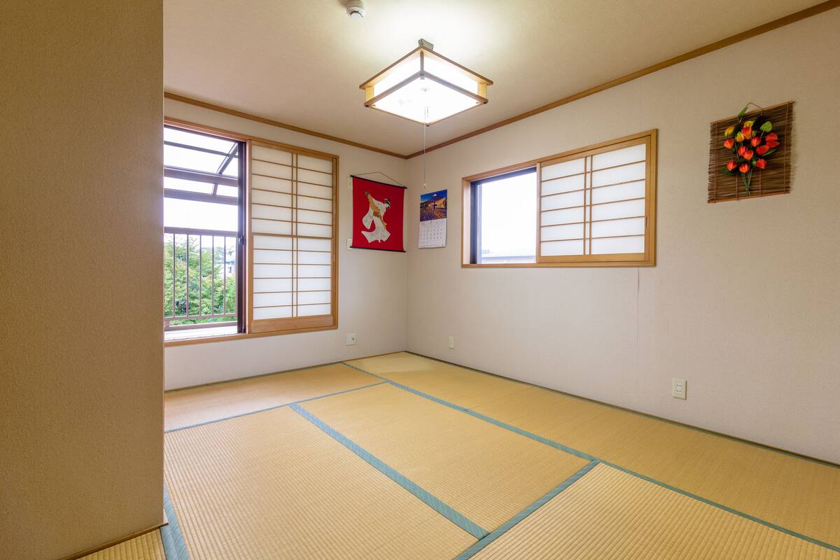Ein traditioneller japanischer Raum mit Tatami-Böden, Shoji-Schirmen und einer hängenden Blumenkomposition.