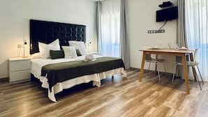 Habitació d'hotel moderna amb un llit gran, una taula de treball i un televisor pla fixat a la paret.
