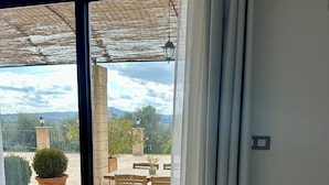 Zona de menjador amb una taula preparada per a dues persones, vistes al pati i una pèrgola amb un fanal penjant.