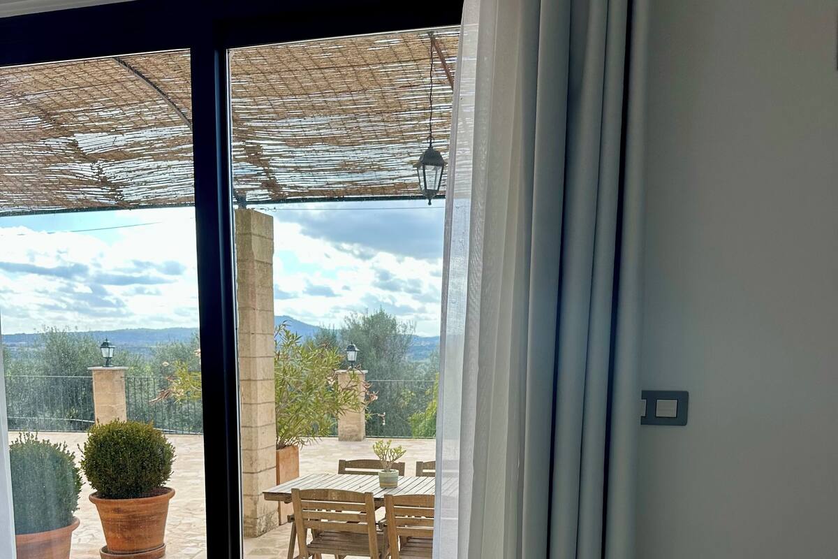 En matplats med ett bord dukat för två personer, utsikt över uteplatsen och en pergola med en hängande lykta.