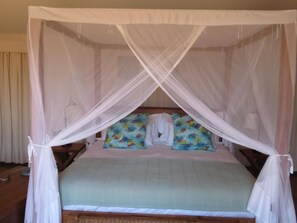 A bed with a canopy, two colorful pillows, and a plain wall. - Vertigo Lodge de Estuario (Inhambane)