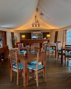 A dining area with wooden tables and chairs, a buffet counter, and a hanging light fixture. - Vertigo Lodge de Estuario (Inhambane)