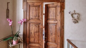 A wooden double door with a 'WELCOME' sign, a potted orchid, and a heart-shaped decoration on the wall. - Il Pozzo Fiorito Residence (Cossombrato)