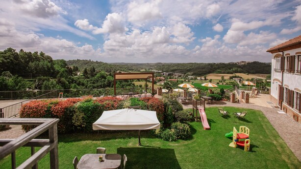 A garden with a table and chairs, a children's play area, and a view of the countryside. - Il Pozzo Fiorito Residence (Cossombrato)