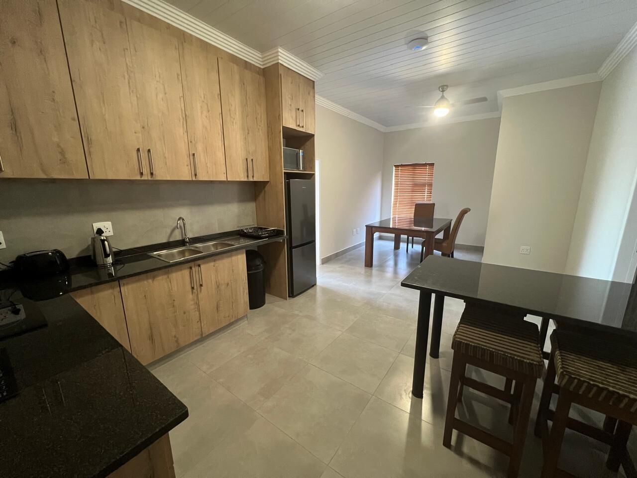 A kitchen with wooden cabinets, a refrigerator, and a dining area with a table and chairs.