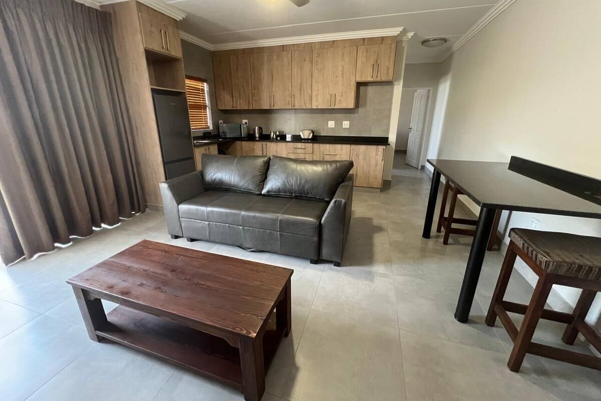 A modern living room with a sofa, coffee table, and dining table.