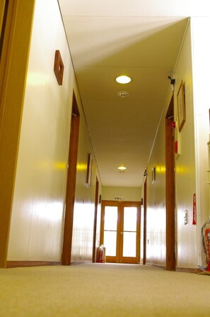 Passadís d'hotel amb portes de fusta, sòl amb moqueta i sostre amb llums empotrades.