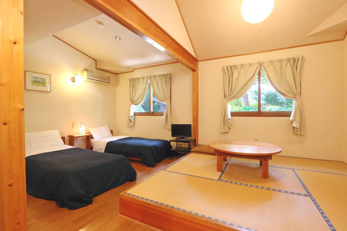 A room with two beds, a small table, and a television.