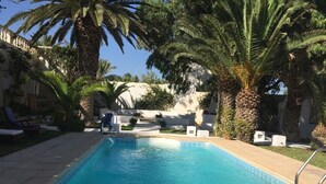 Una piscina al aire libre, sombrillas, sillones reclinables de piscina