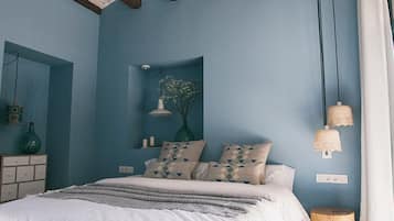 A bedroom with a bed, bedside tables, a mirror, and a hanging light fixture.