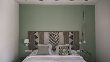 A bedroom with a bed, a wall-mounted lamp, and a hanging light fixture.