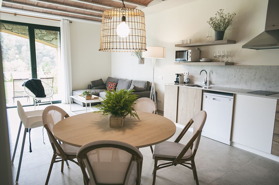 Une cuisine moderne avec une table ronde en bois, des armoires blanches et un lave-vaisselle encastré.