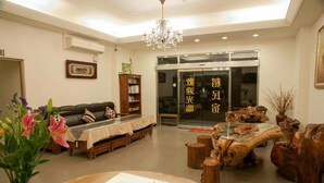 A well-lit living room with a sofa, a coffee table, and a chandelier. There is a bookshelf and a glass door with Chinese characters. - Rice Countryside B&B (Dongshan)