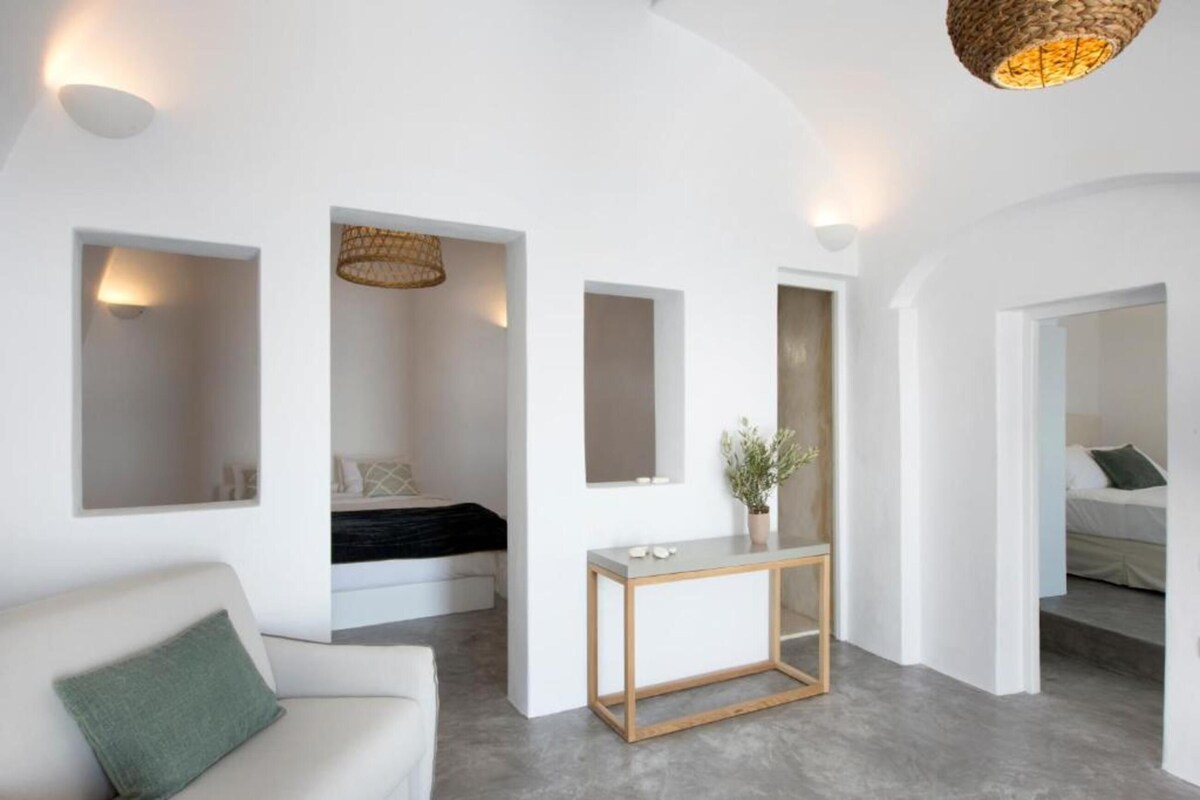 A modern interior with a white couch, a console table, and a bed with a black headboard.