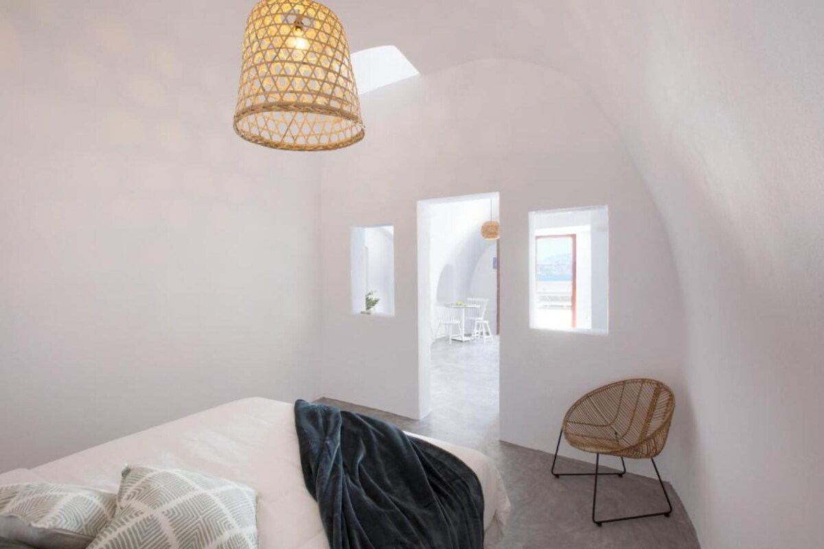 A modern bedroom with a bed, a chair, and a hanging light fixture.